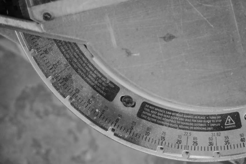 DIY blogger measuring crown molding angles with a bevel protractor in a sunlit living room